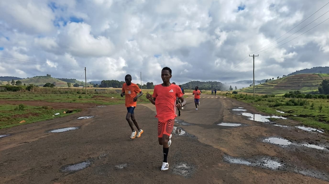 Running coach on a Kenyan dirt road with tea fields in the background